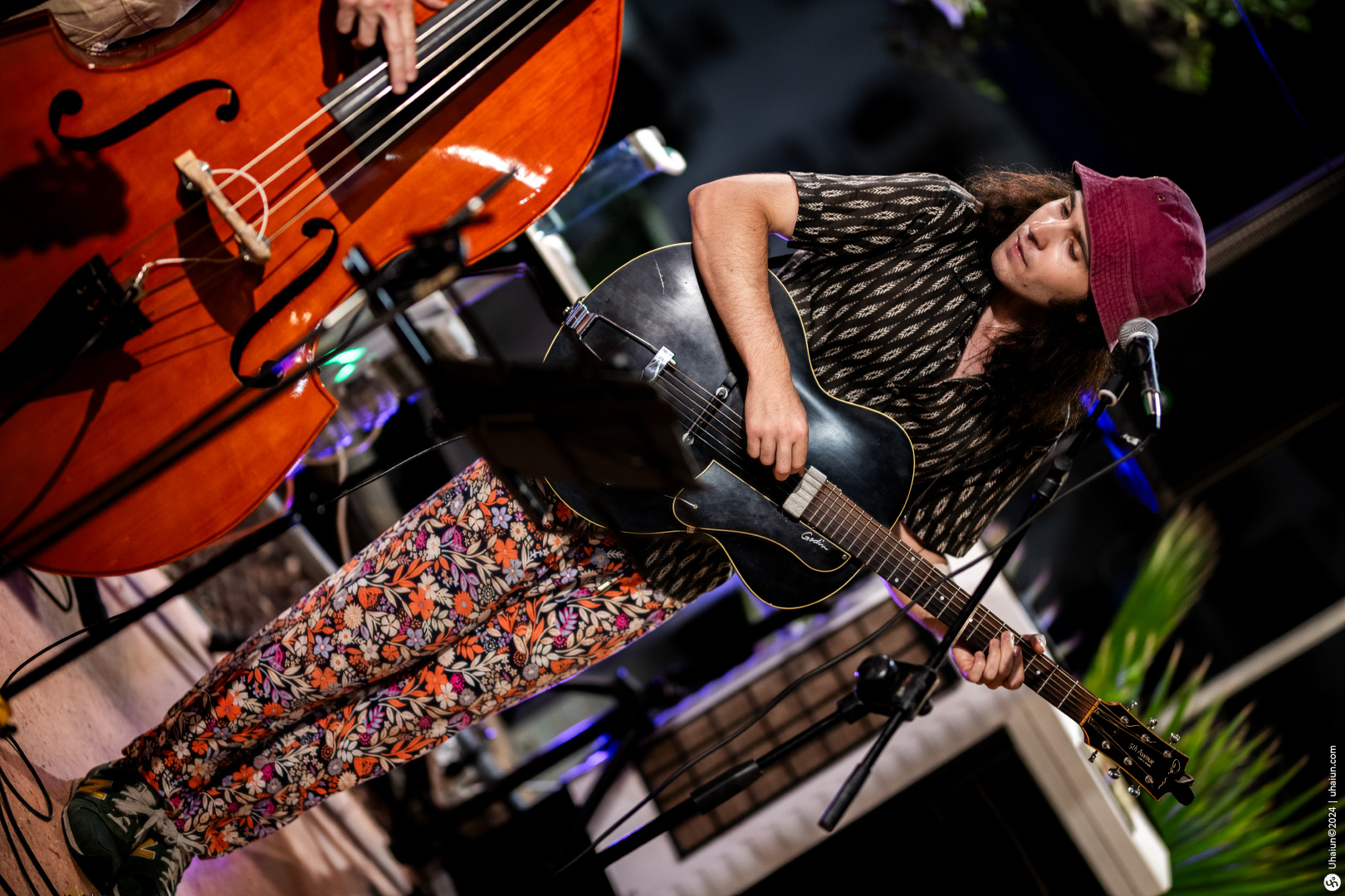 Musician playing guitar on stage with double bass