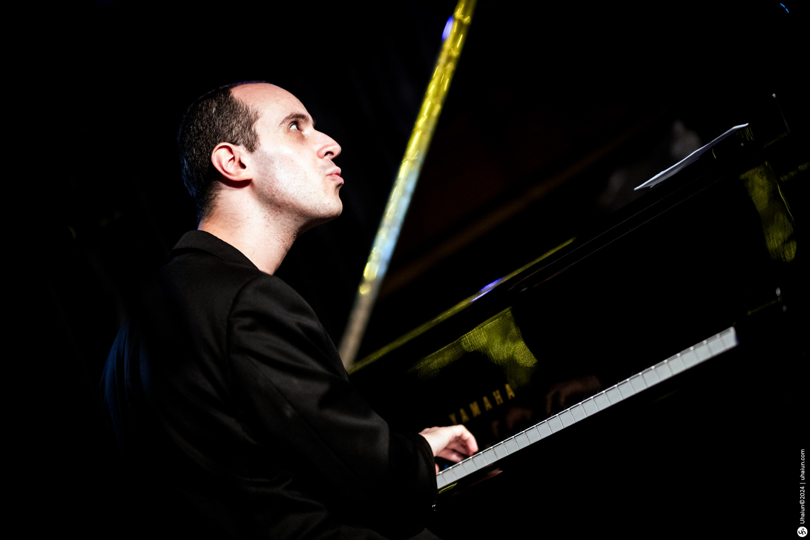 Pianist in black performing on stage at night