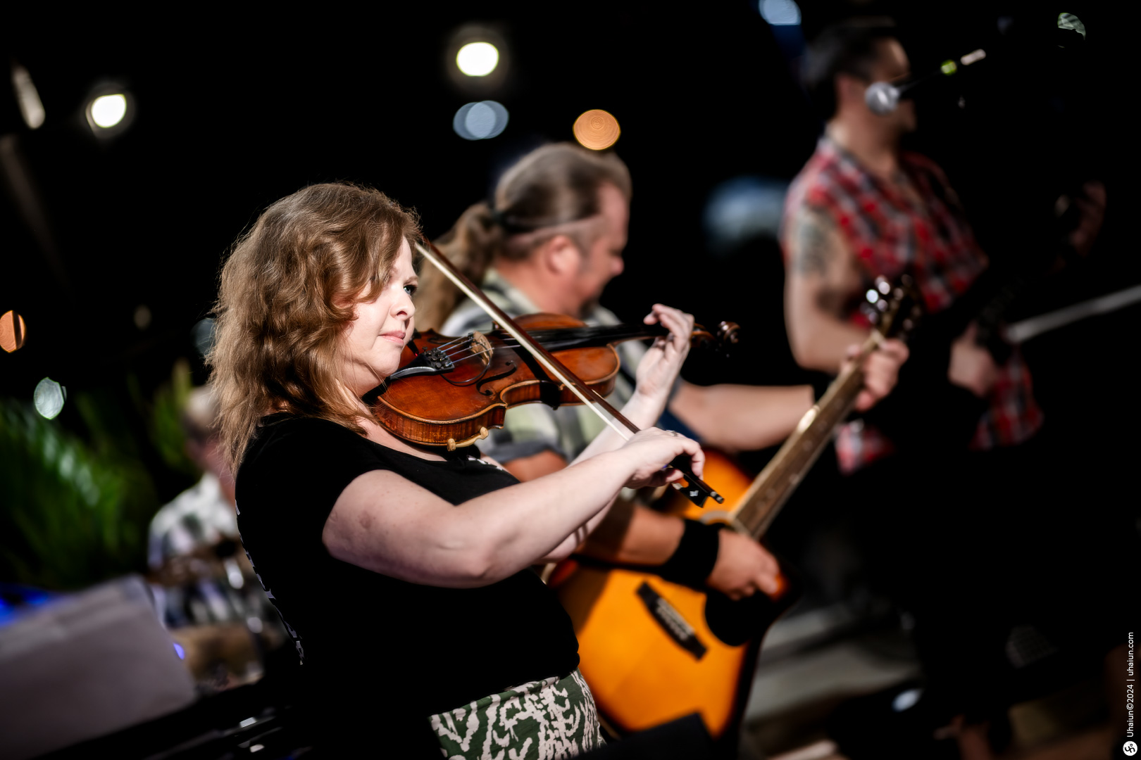 Woman playing violin in live music band performance