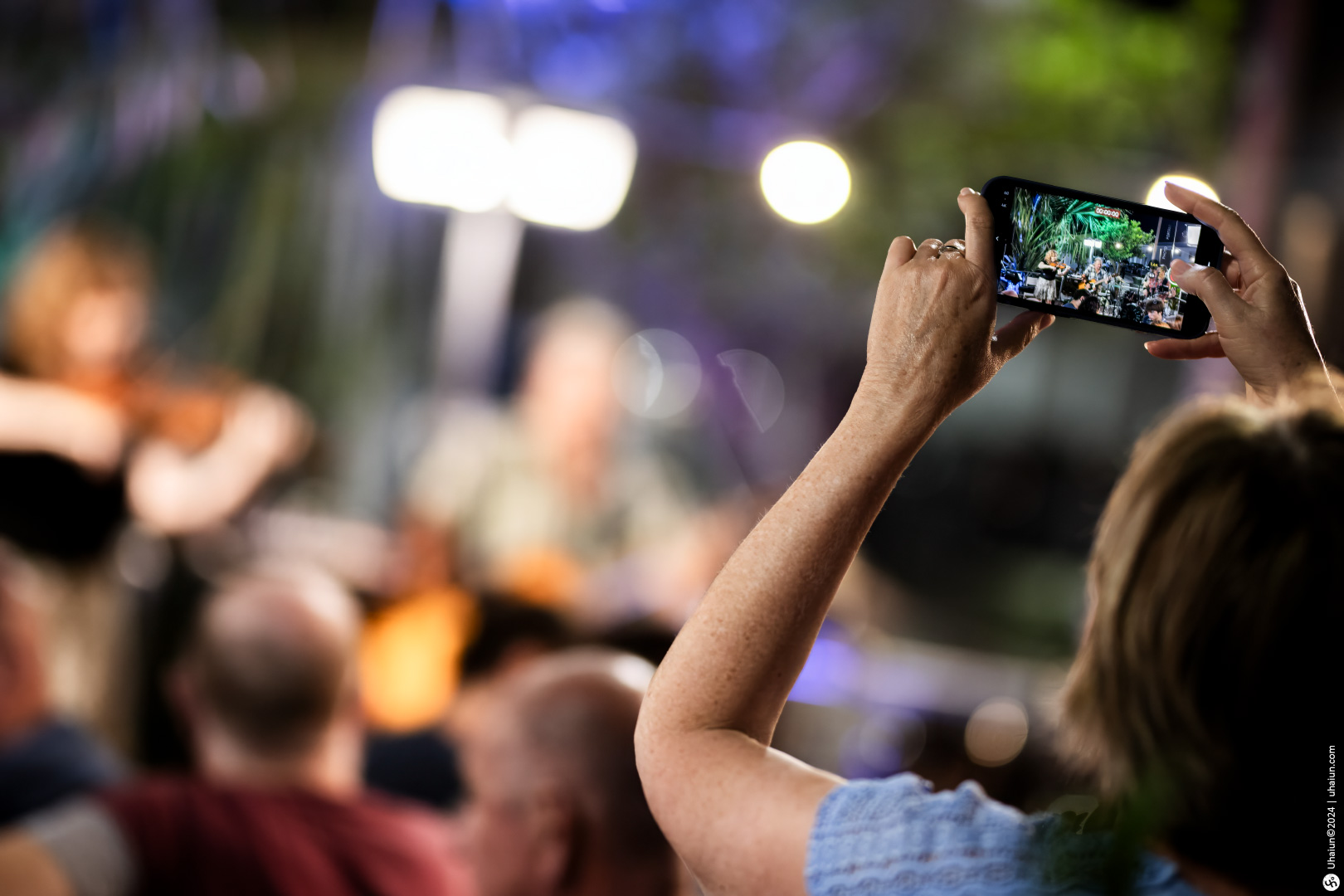 Person recording live music performance on smartphone