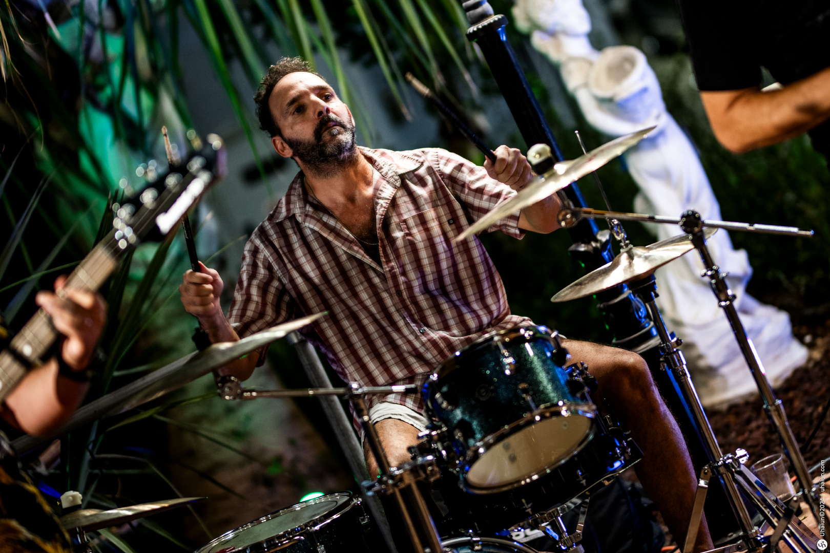 Drummer performing energetically on stage with band