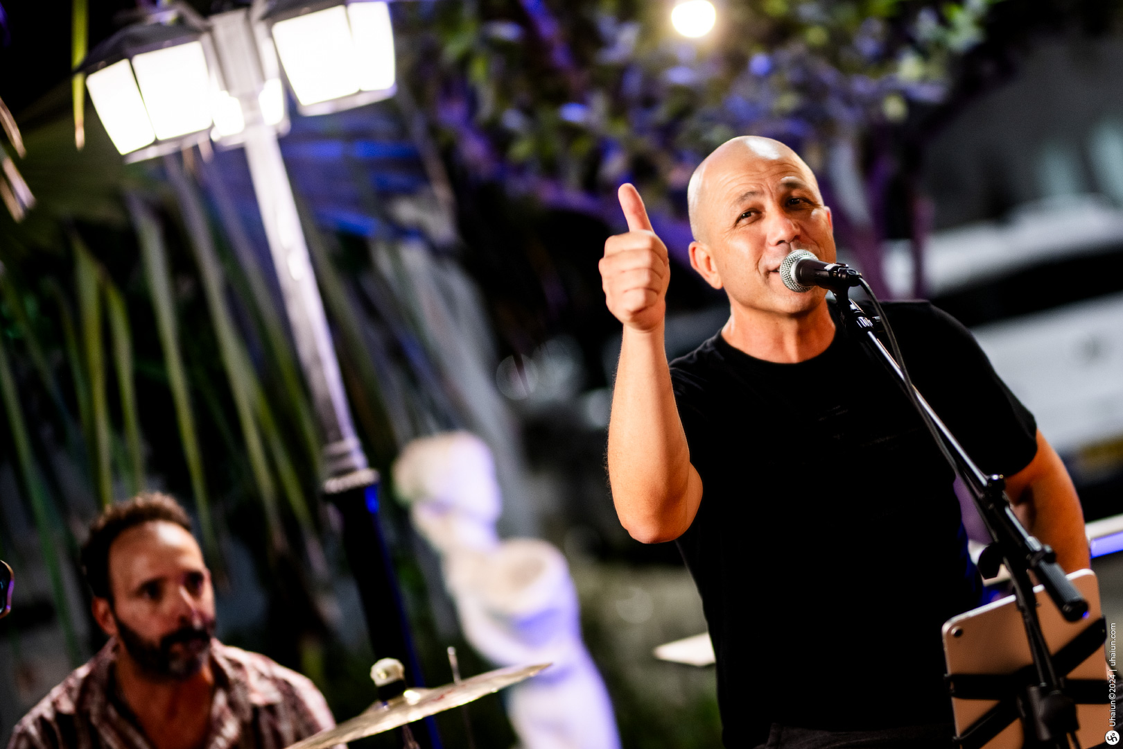 Man singing on stage with microphone thumbs up