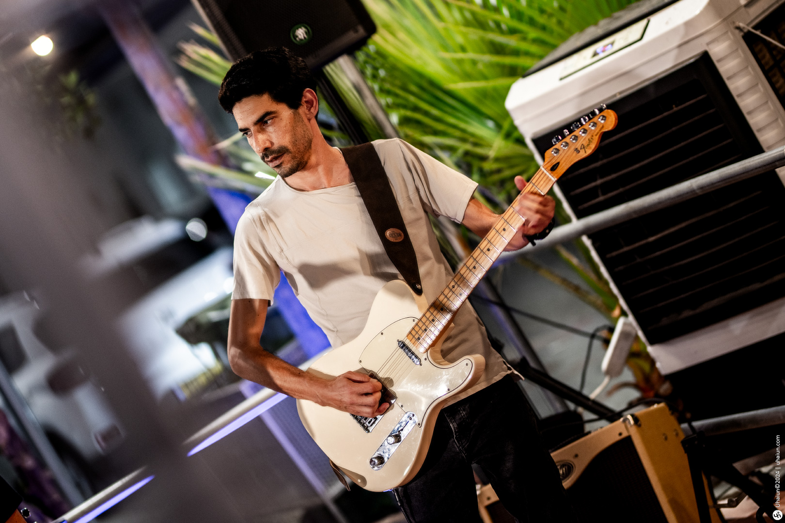 Guitarist playing white electric guitar on stage