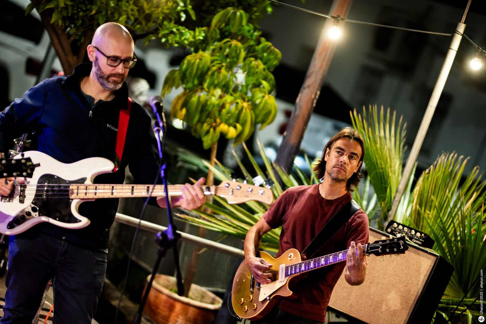 Musicians performing outdoors with guitars at night