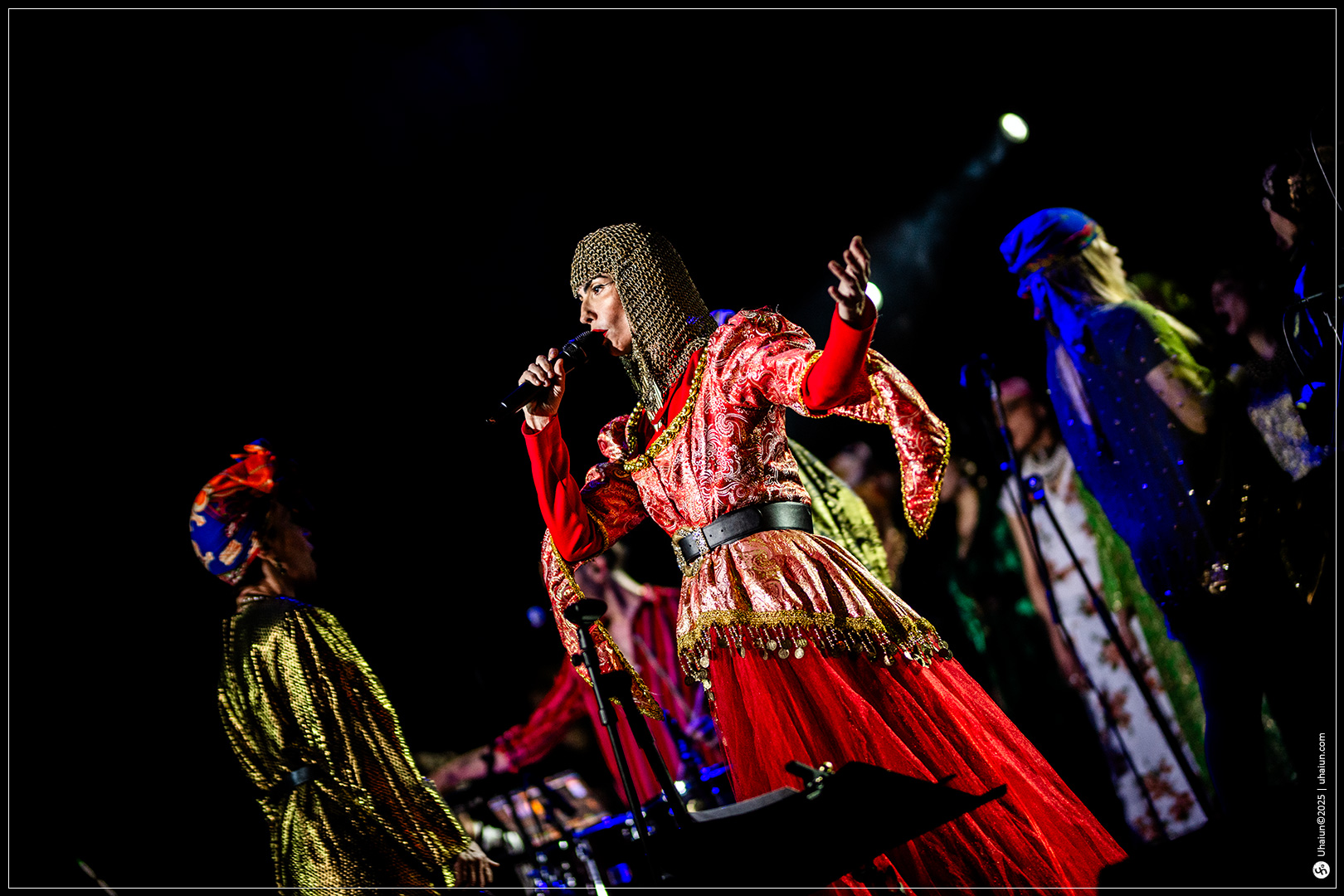 Performer in vibrant costume singing on stage