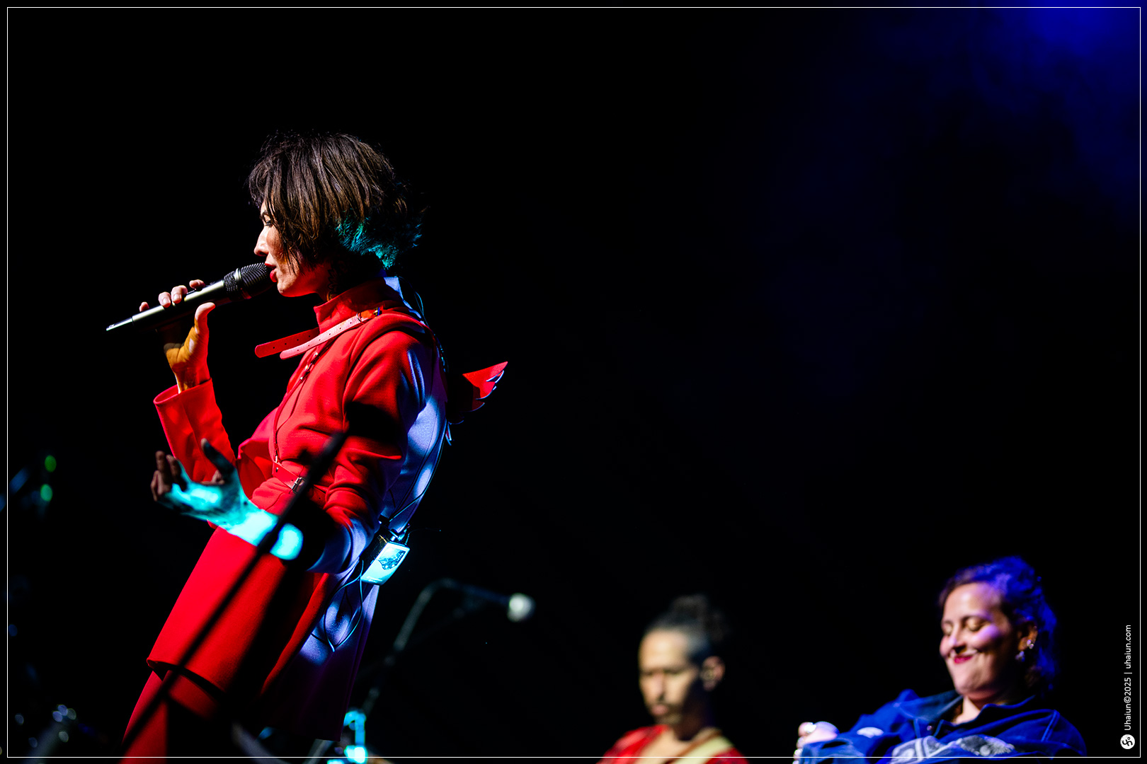 Performer singing on stage under colorful lights