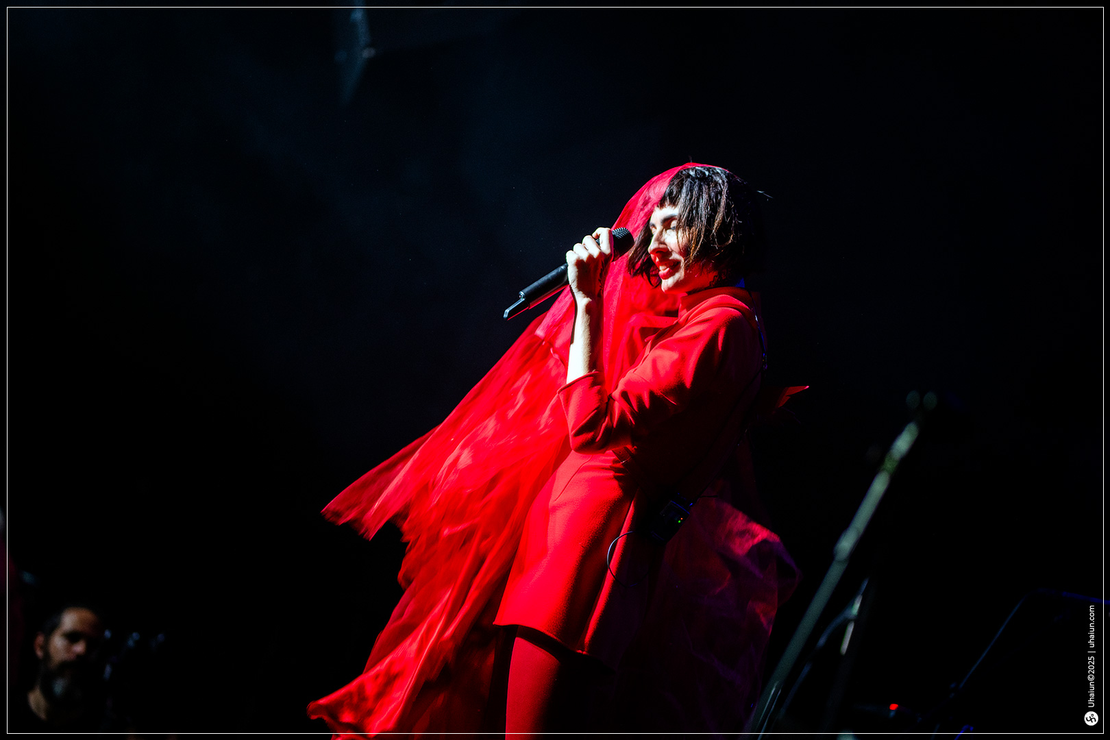 Performer in vibrant red on stage singing