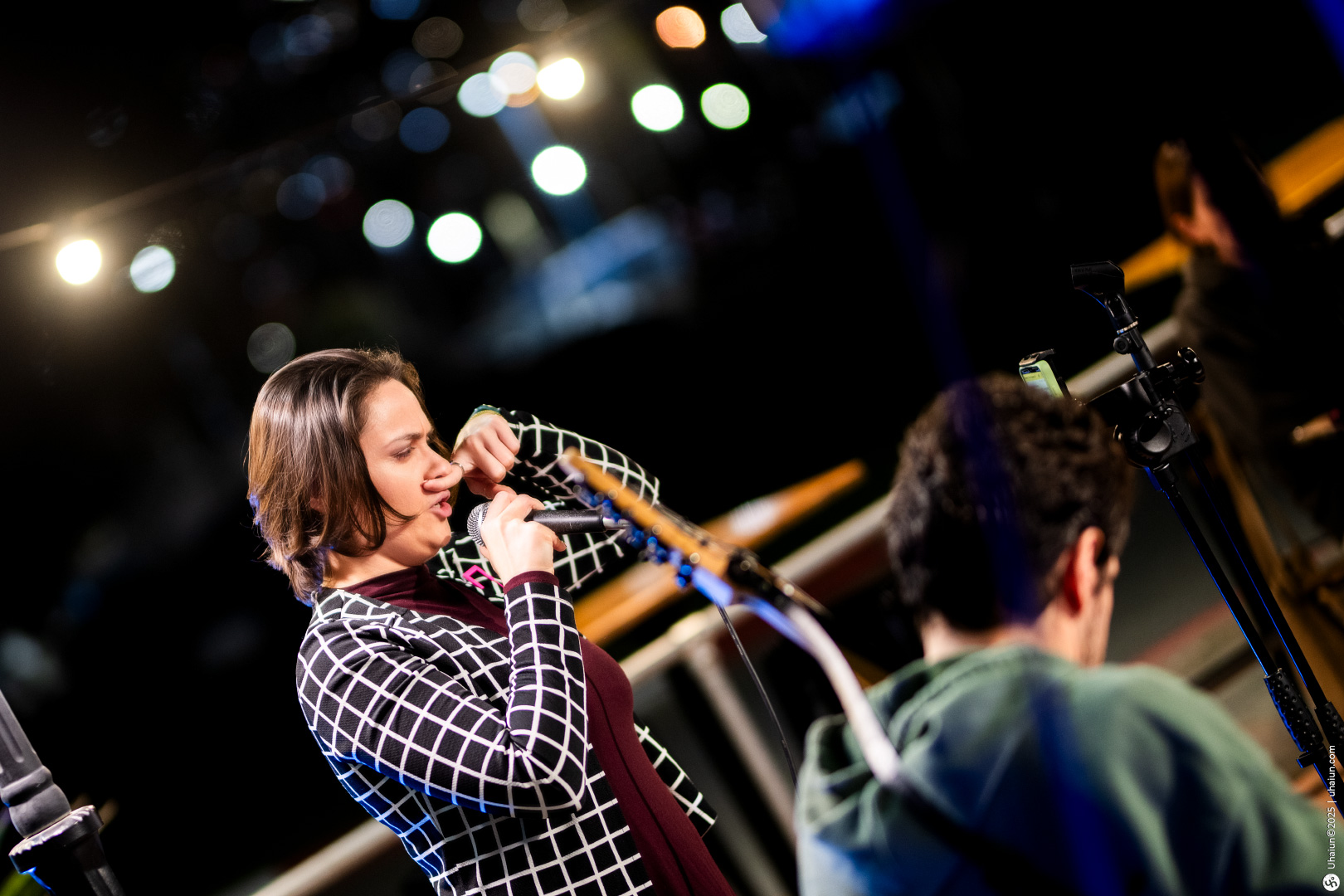 Woman singing into microphone on stage outdoors