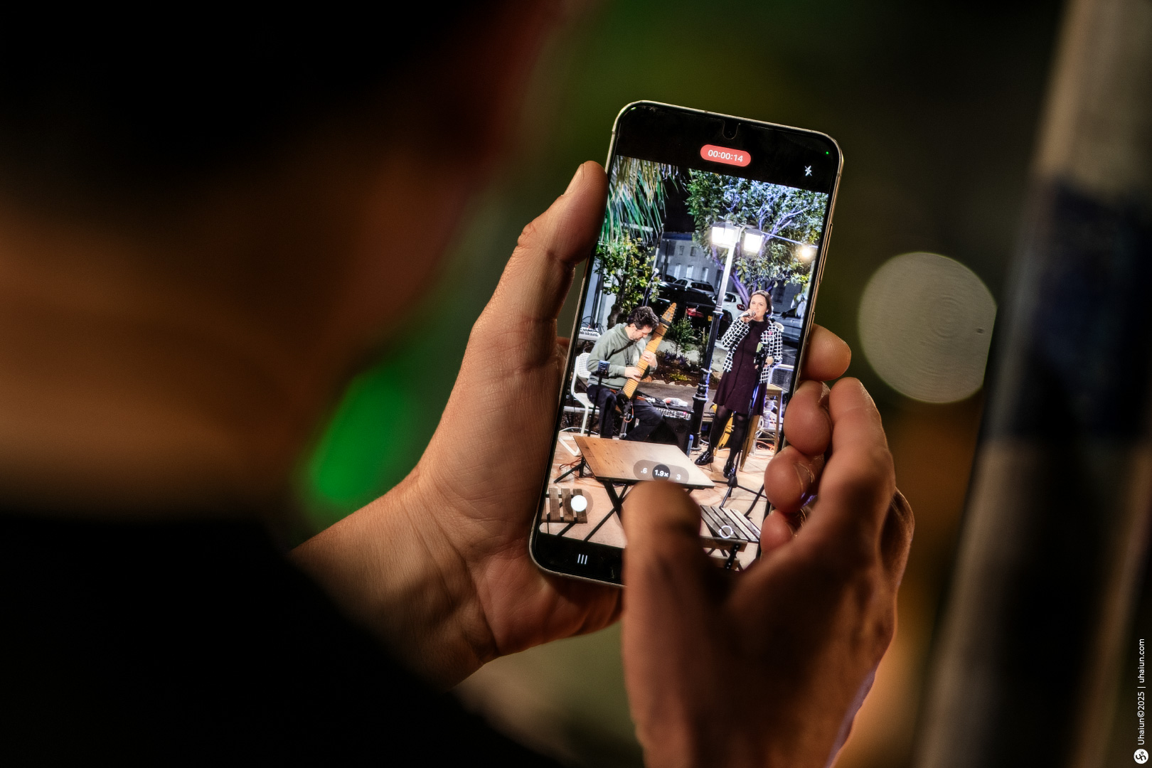 Person photographing musicians on smartphone at night