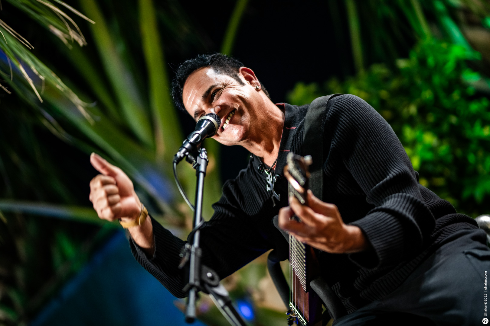 Man performing on stage with guitar outdoors