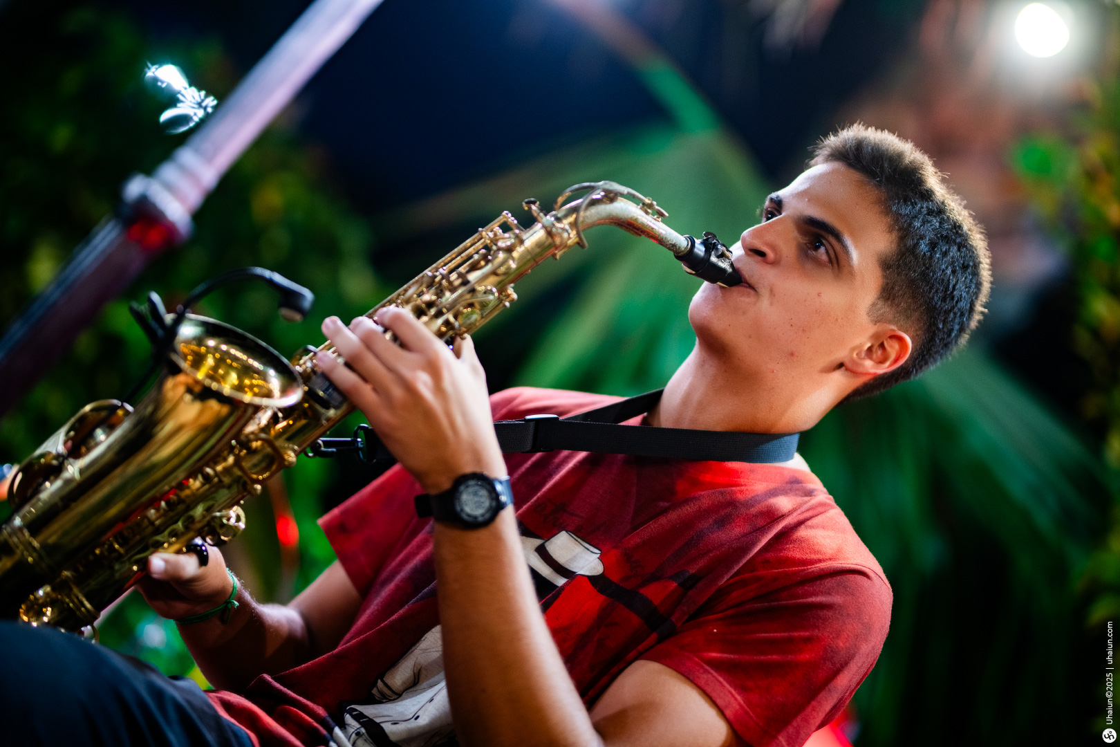 Young man playing saxophone at night outdoors