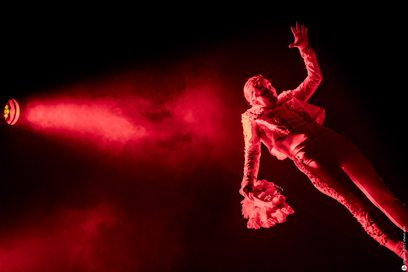 Performer in dramatic red spotlight poses gracefully