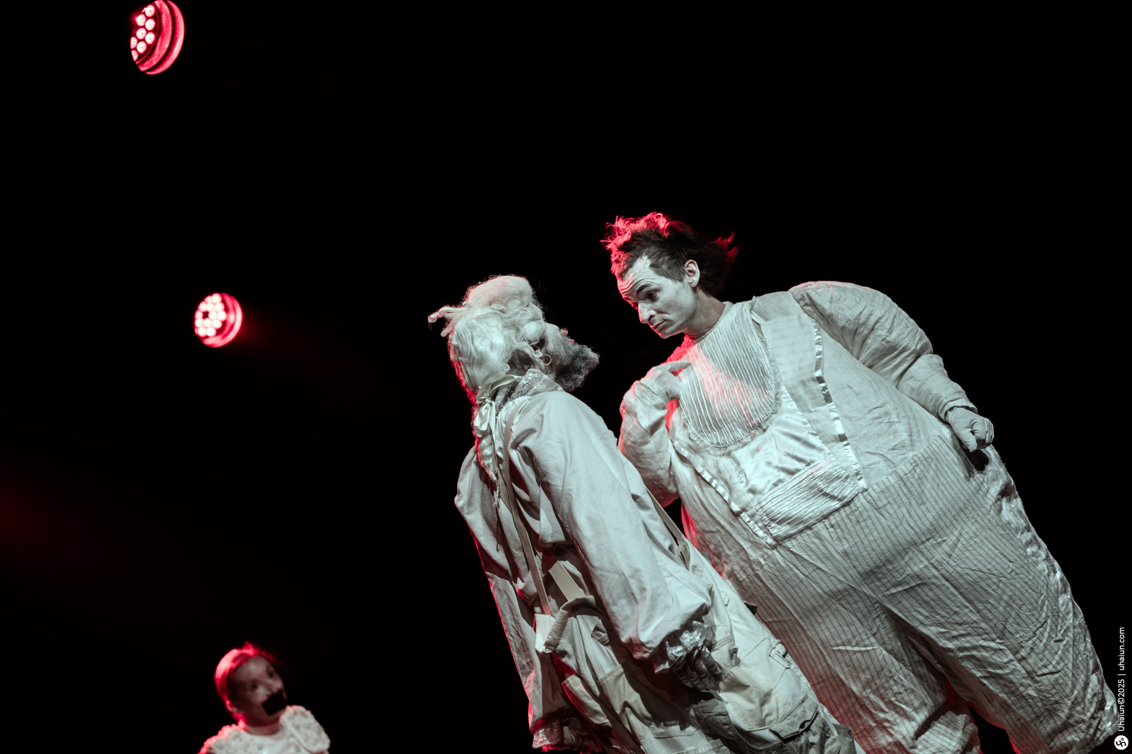 Clowns performing on stage under red lights