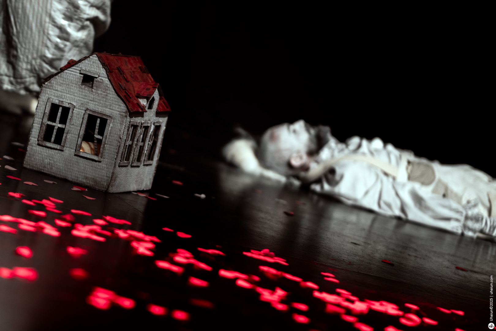 Creepy scene with dollhouse and person lying