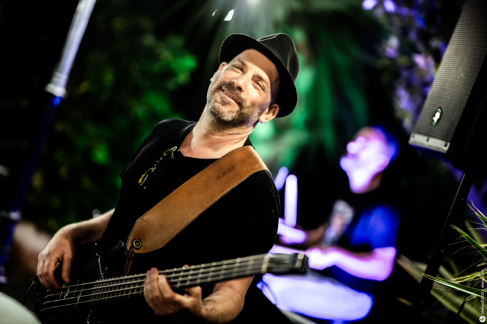 Smiling musician playing bass guitar with drummer behind