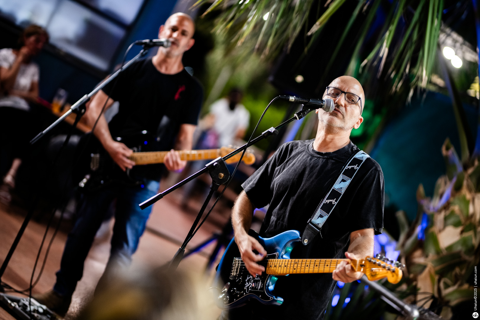 Two guitarists performing live on stage together