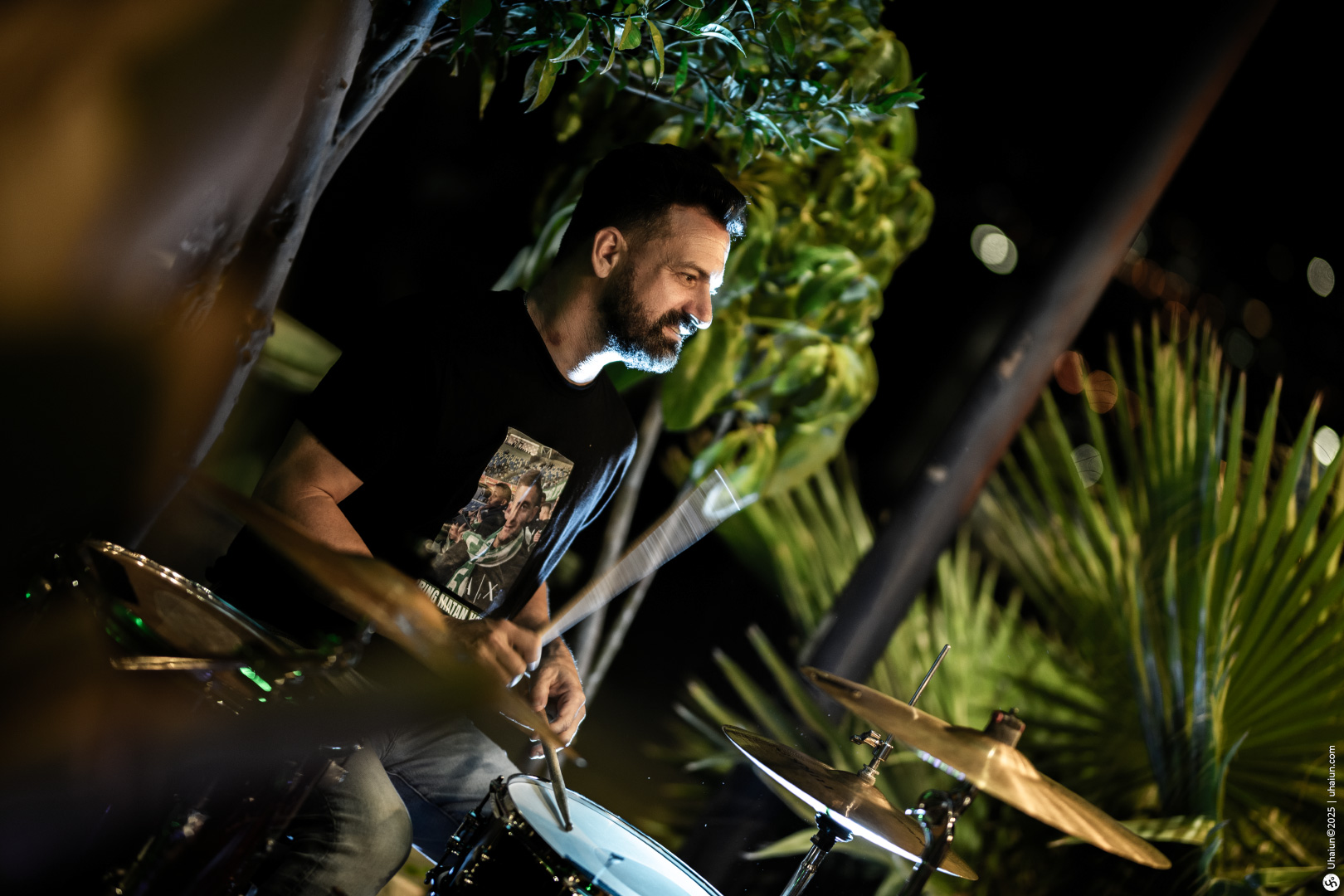 Drummer playing music outdoors among plants