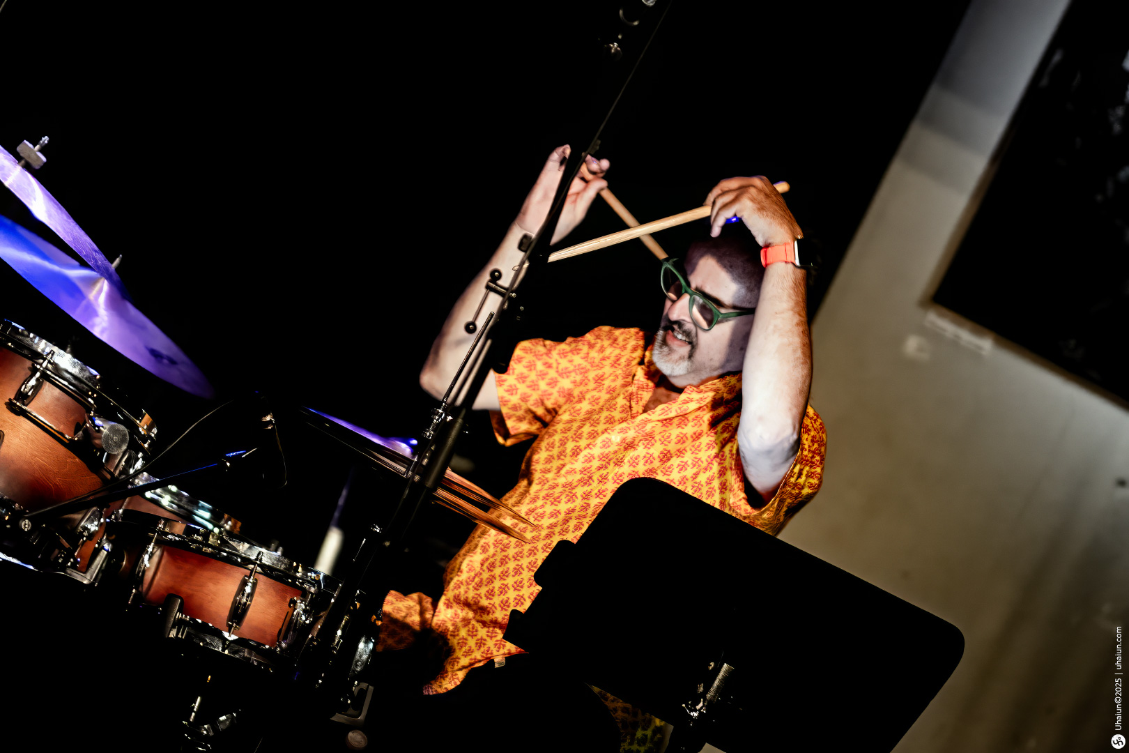 Drummer performing energetically on stage with drums