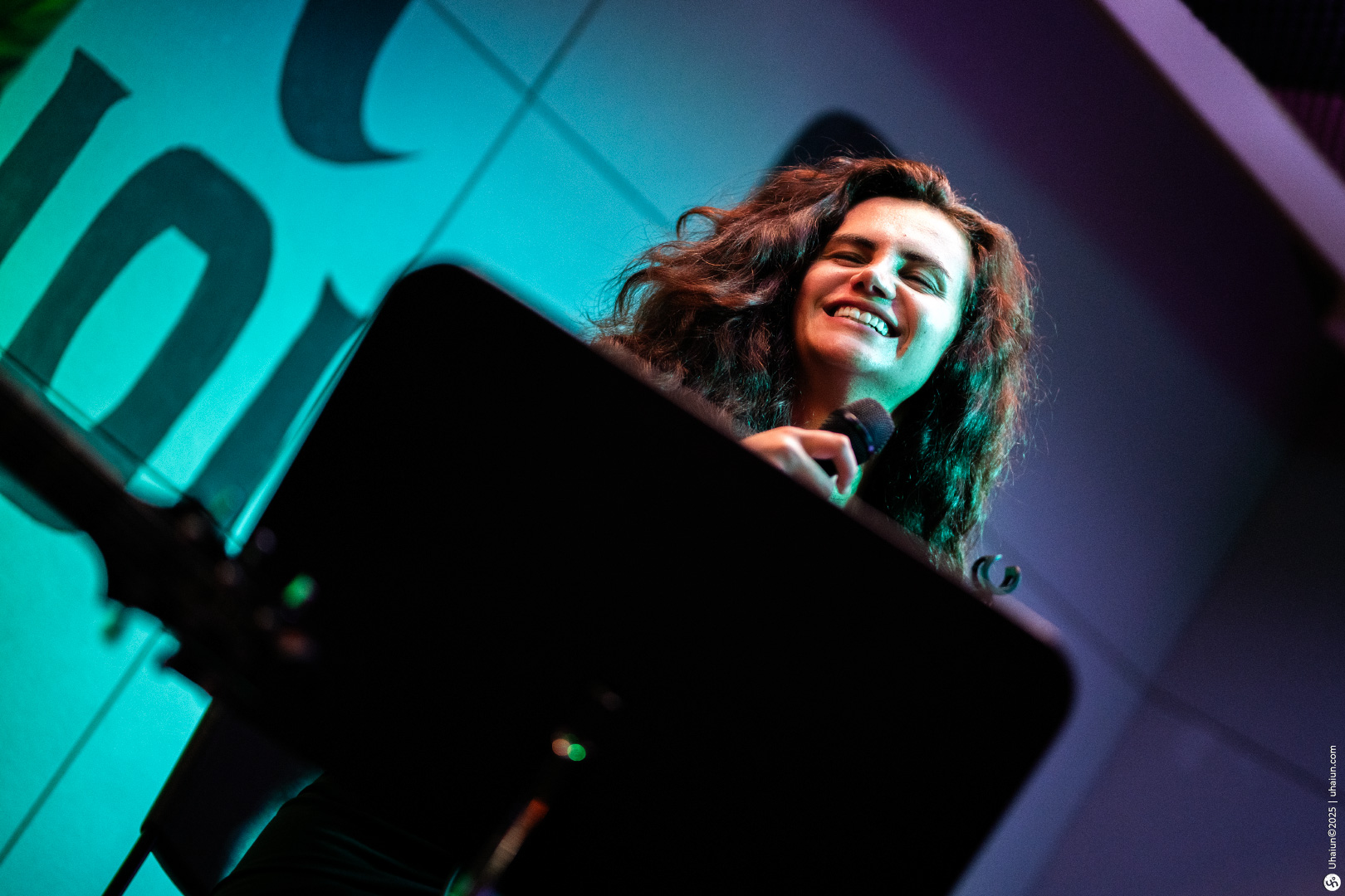 Woman smiling while holding a microphone onstage