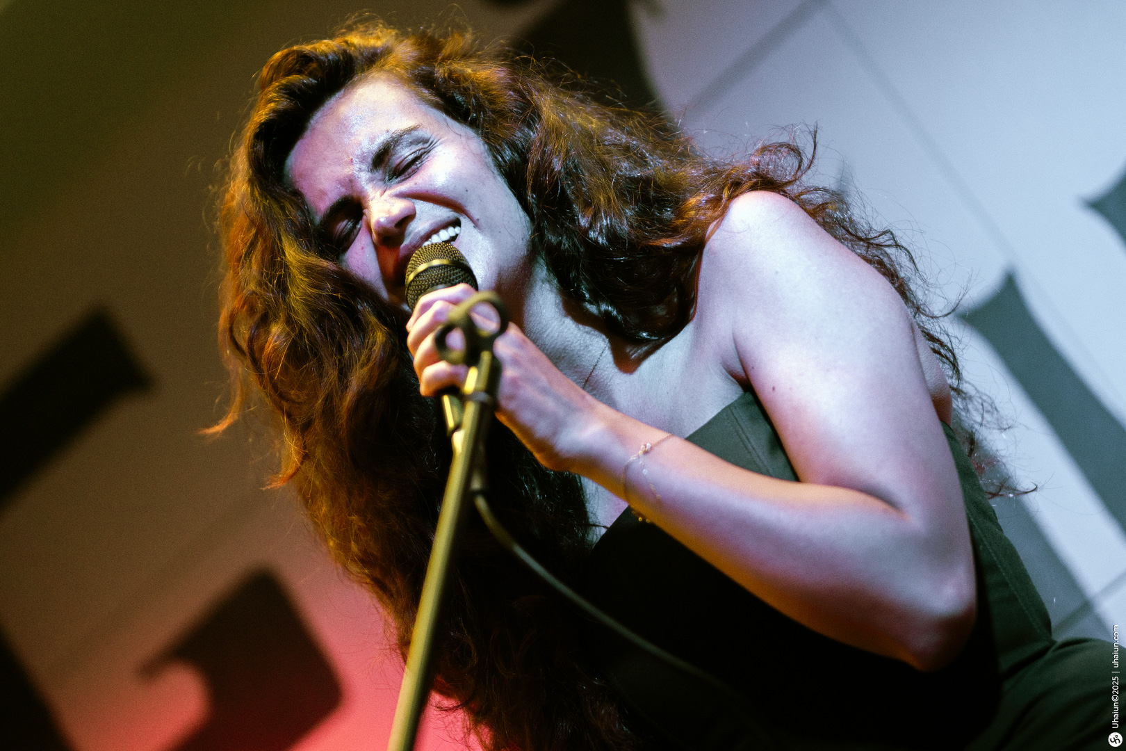 Woman singing passionately on stage with microphone