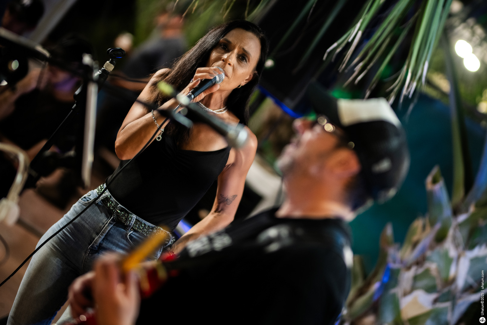 Singer performing with guitarist on stage outdoors