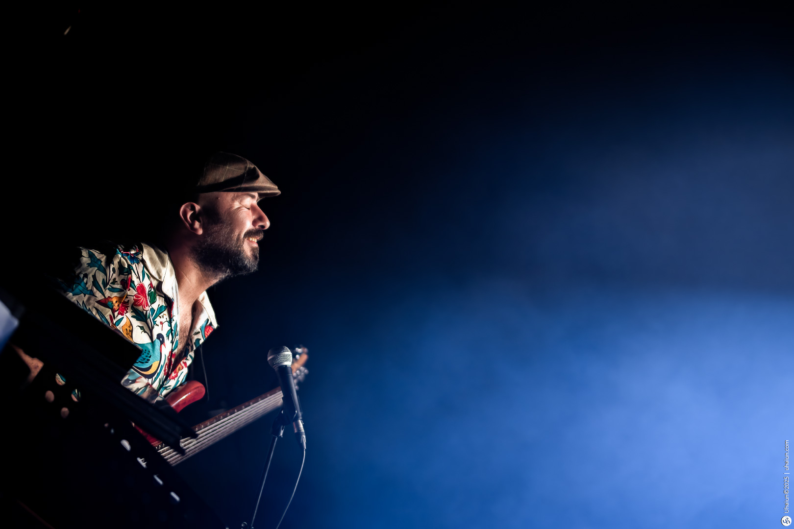 Musician playing guitar on dimly lit stage