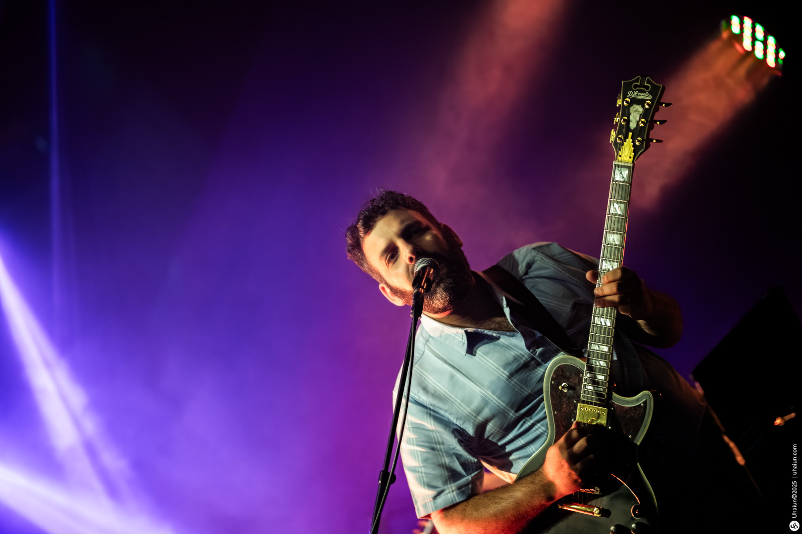 Guitarist performing live on stage with spotlight